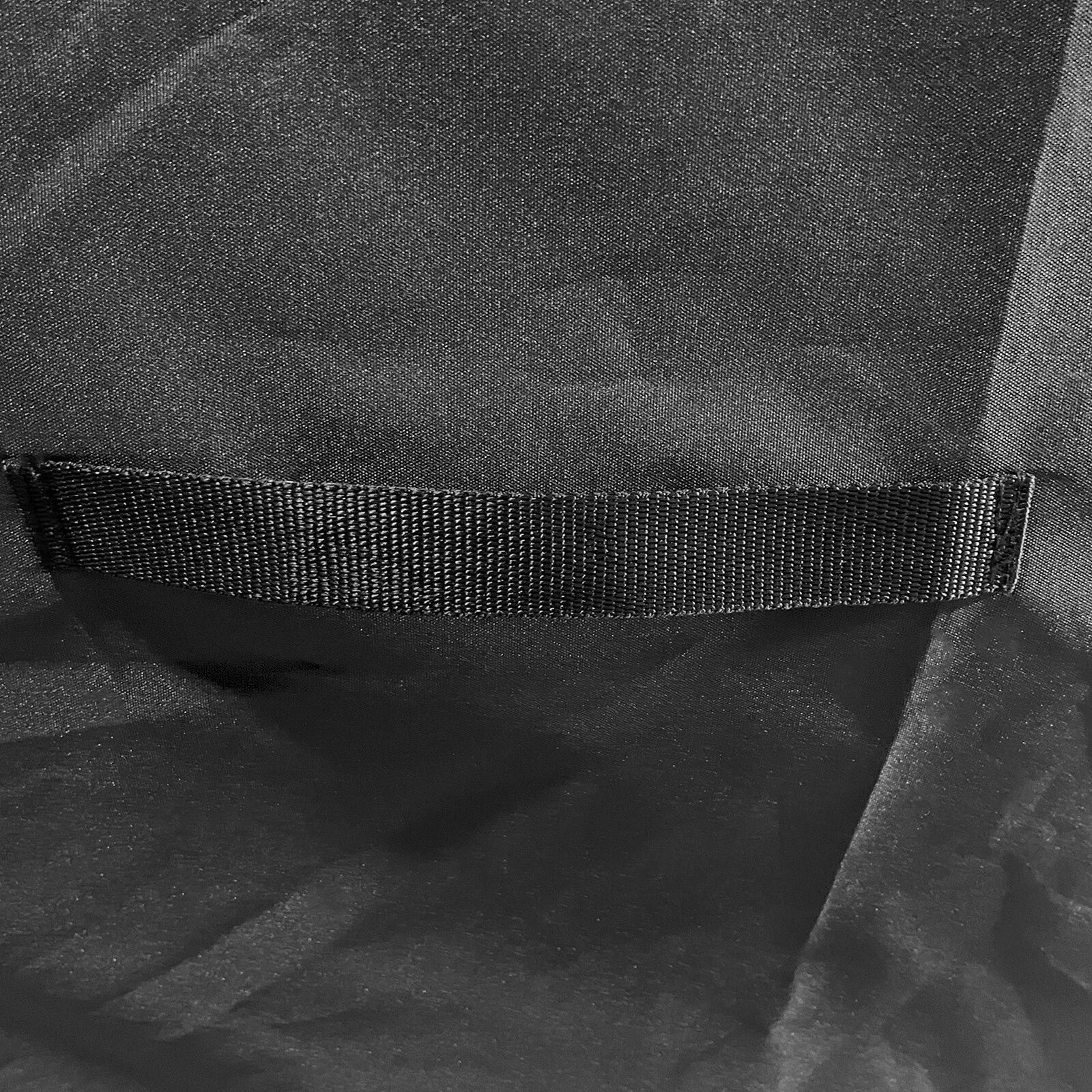 Close-up of a black textured fabric item with a horizontal black elastic or hook-and-loop style band across the middle.