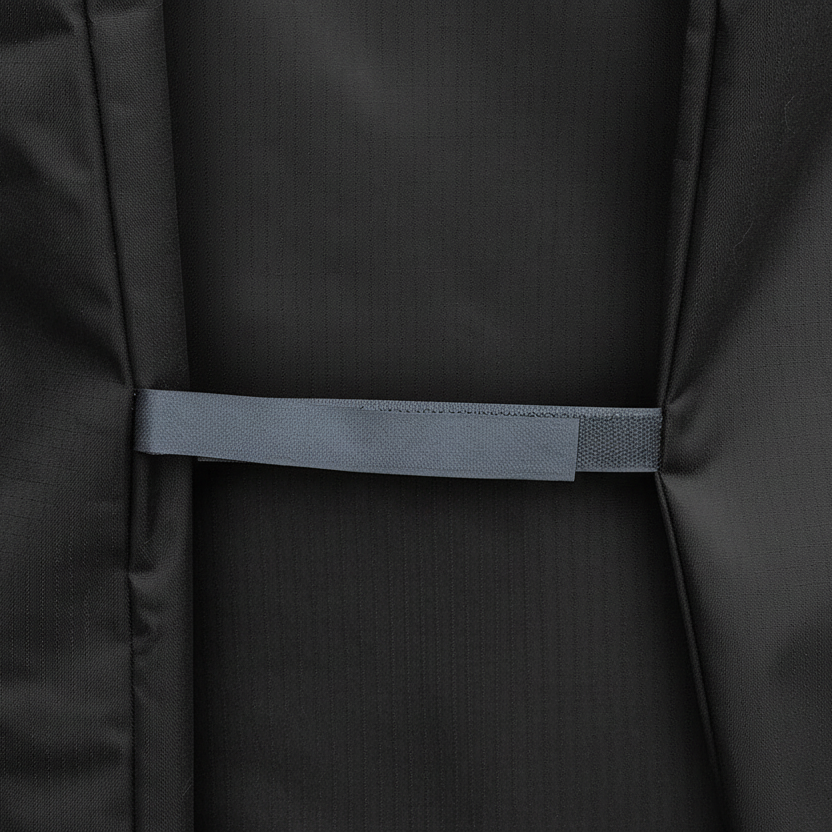 Close-up of a black textured fabric item with a horizontal gray velcro strap  across the center