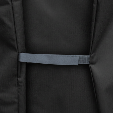 Close-up of a black textured fabric item with a horizontal gray velcro strap  across the center